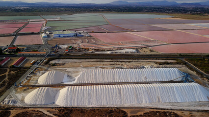 Aerial drone view of colorful salt evaporation ponds and white salt piles near Santa Pola, Spain,...