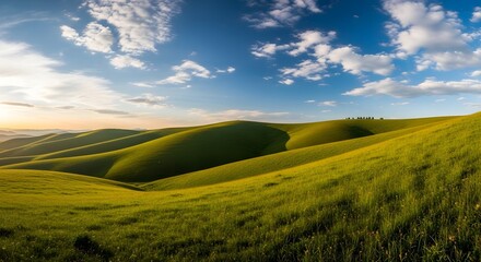 Obraz premium A scenic view of rolling green hills under a partly cloudy blue sky during the daytime in the countryside