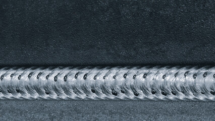 Close-up of metal part with weld seam, the part lies on metal production table in factory or telloconstruction plant as industrial metal concept background.