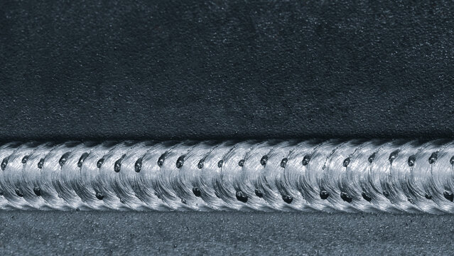 Close-up of metal part with weld seam, the part lies on metal production table in factory or telloconstruction plant as industrial metal concept background.