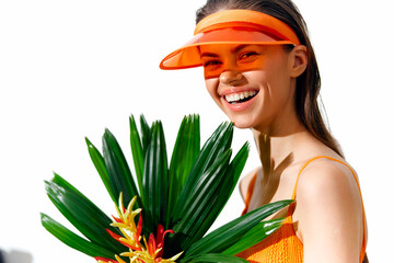 Cheerful young woman in vibrant orange outfit with tropical foliage, smiling brightly against a...