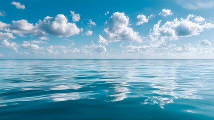 Obraz premium Expansive turquoise water stretches toward a horizon beneath a vibrant blue sky dotted with white fluffy clouds