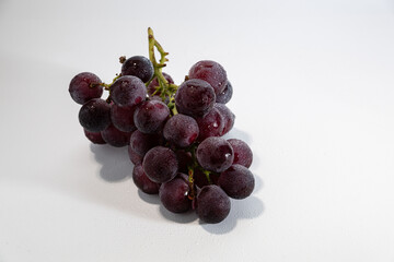 A Bunch of Fresh Red Grapes with Dew Drops on a White Background
