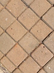Obraz premium Close-up of a paved surface featuring diamond-shaped interlocking concrete blocks in varying shades of brown and gray.