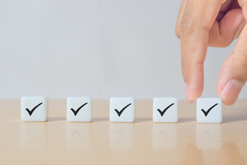 Checklist Survey and assessment concept, human hand putting dice with Check mark icon on wooden blocks, gray background with copy space
