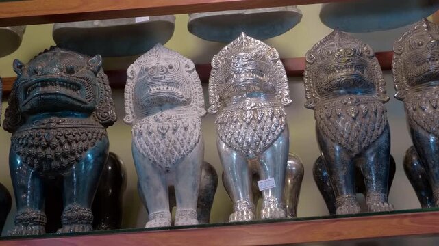 On the shelf, bronze snow lion statues glitter in the light and sold on the flea market for memory of a trip to Siem Reap, Cambodia. Closeup. Shot in motion
