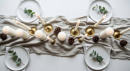 Table setting white plates eucalyptus lit candles pine cones gray cloth on white surface