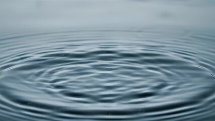 A detailed image of a water droplet impacting the surface, causing circular ripples - Powered by Adobe