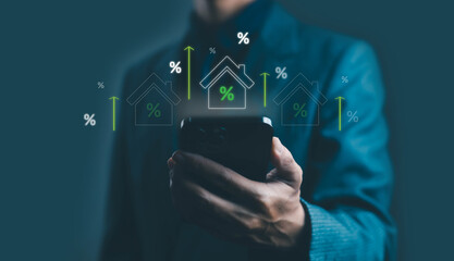 Businessman using smartphone with virtual rising house icons and percentage signs, symbolizing real estate growth, mortgage interest rate, property investment, and housing market financial concept.