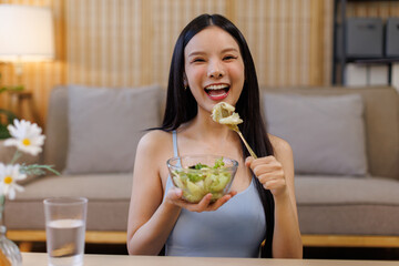 Happy multiracial asian woman eating healthy salad for lunch at home office.Break from work. Copy space. Healthy lifestyle concept.