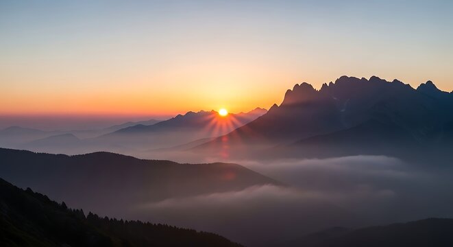 A breathtaking sunrise illuminates jagged mountain peaks and valleys filled with misty clouds, creating a serene, panoramic view