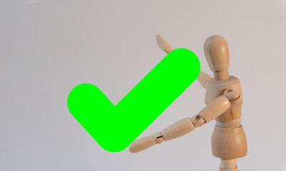 Wooden mannequin holding a giant green check mark