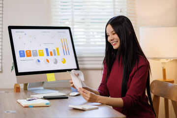 Thoughtful upset asian woman checking receipts and statements at home table with water glass. Payment difficulties, gas electricity charges, housing expenses, late fees, domestic money concerns
