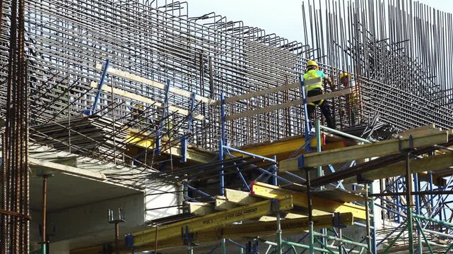 Man worker installing binding wires to reinforcement steel bars on new business centar skyscraper building