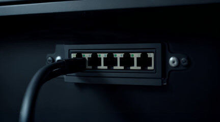 Ethernet cable connected to network router port in dark modern office environment, symbolizing digital infrastructure, data connection, communication, and global internet technology system