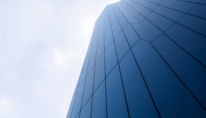 Low angle view of modern skyscraper with curved glass facade under soft blue sky, representing corporate success, ambition, modern architecture, and global business innovation concept