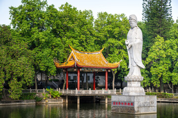 Confucius Statue and Traditional Pavilion in a Serene Park Setting Surrounded by Lush Greenery and a Calm Lake