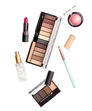 professional makeup assortment including eyeshadow palette, lipstick, blush, and brush, presented as a flat lay collection isolated on a dark background.
