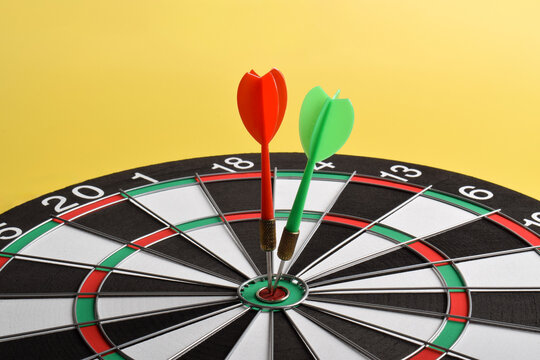 Target hit in the center by arrows. Dart board with arrows isolated on yellow background