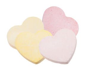close-up photograph of four pastel pink and yellow conversation heart candies clustered together against an isolated solid transparent background.