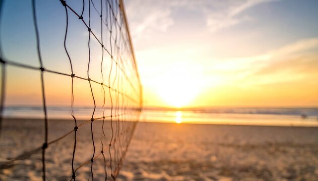Serene beach volleyball court with the net in selective focus against a beautiful, warm sunset over the sea and sand