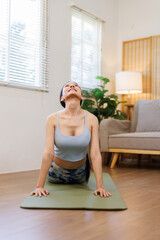 Portrait of an active young asian woman doing yoga or stretching exercise at home
