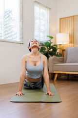 Portrait of an active young asian woman doing yoga or stretching exercise at home
