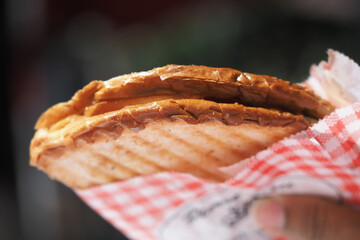 Delicious sandwich served in a checkered wrapper at a market