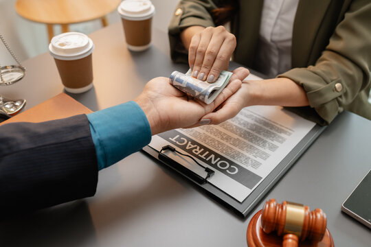 A businesswoman is handing over cash to a lawyer in an office, representing corruption, bribery, or illegal payment. The scene highlights unethical financial transactions and law violation.