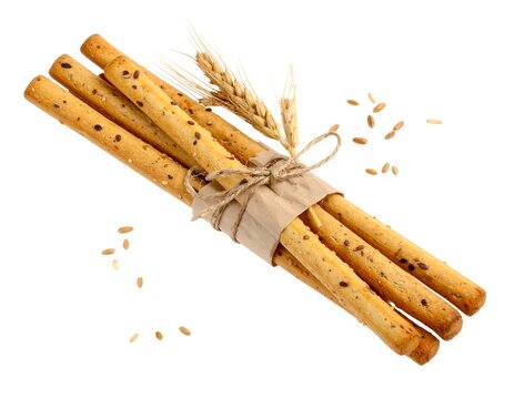 Bunch of breadsticks tied with twine, wheat sprig, and scattered grains