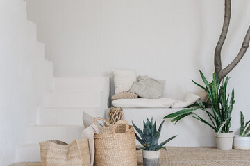 Beautiful handcrafted jute baskets standing on a soft rug near lush green plants. Natural home decoration in boho and eco style. Warm light, neutral colors and textures create a calm and cozy interior