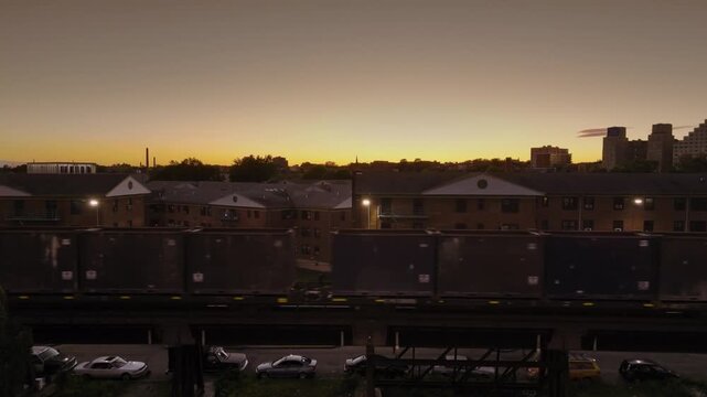 aerial view of industrial freight trait cargo traveling slowly near a urban residential area at sunset.
