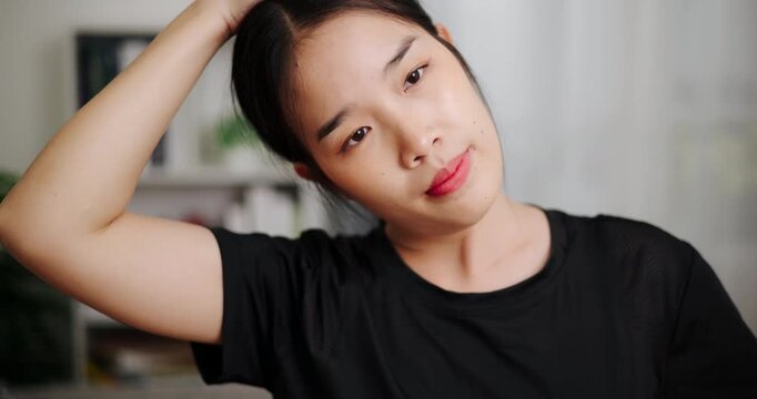 Handheld selective focus shot, Relaxed Asian woman is exercising by stretching in the living room at home. Healthy Lifestyle Concepts. Women Lifestyle