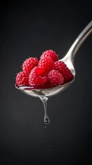 Close-up of ripe red raspberries on spoon, with clear liquid