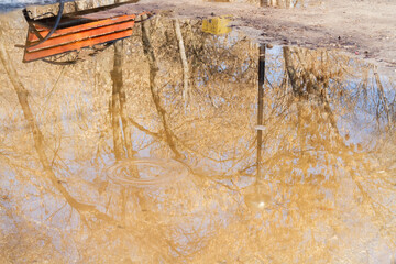 Wooden bench in the spring park. Bright spring sun and snow in the park. Place to rest for a walk. Morning walk..