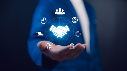 Global digital business handshake concept. A professional holds icons representing worldwide partnership, speed, logistics, teamwork, and integrated solutions for corporate success.