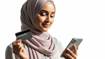 A woman in a hijab uses a phone and credit card, smiling. Background is simple white - Powered by Adobe