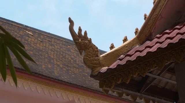Golden chofas (traditional Asian serpent-like roof decorations) on the roof of Wat Svay Romeat Pagoda, Siem Reap, Cambodia. Shot in motion