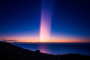 A shimmering light pillar appearing over the sea at twilight