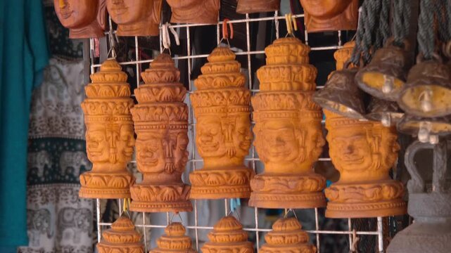 Wood carved Buddha face masks hang on a counter wall on a flea market in Siem Reap, Cambodia. Closeup. Shot in motion