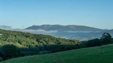 Obraz premium Serene mountain landscape with misty valleys and lush green hills