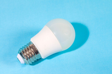 A modern, white LED light bulb isolated against a plain light blue background. A concept for ideas, innovation, illumination, energy saving, and technology.