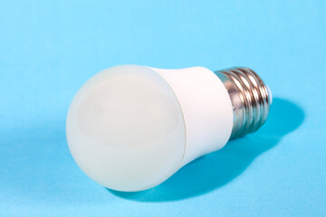 A modern, white LED light bulb isolated against a plain light blue background. A concept for ideas, innovation, illumination, energy saving, and technology.