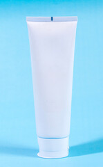 Mockup of a plain white cosmetic or cream tube, isolated on a light blue background. A blank template ready for your product branding and design.