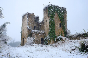 An abandoned castle, its towers and ivy-covered walls draped in the season first snow