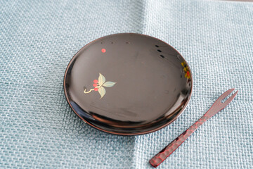 青いマットに黒皿と赤いフォークの構図