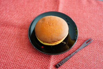 黒皿の上のどら焼きと赤いフォーク