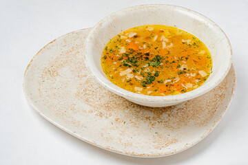 A bowl of steaming chicken soup is served, garnished with fresh dill and chopped carrots
