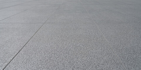 Textured grey granite-like floor tiles with visible grout lines in a repeating pattern and perspective.