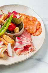 A Charcuterie Board offers salami, Prosciutto, pickles, tomatoes, and small skewers with vegetables